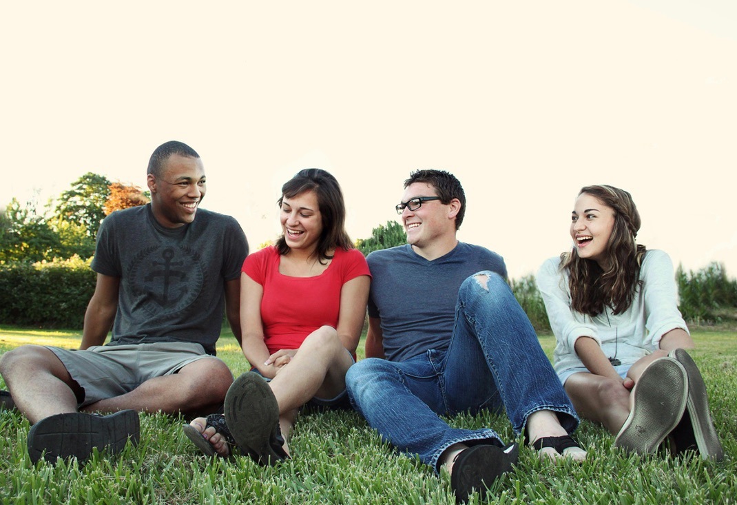 Friends sitting together on grass in sunlight